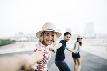 Spain, Barcelona, portrait of smiling young woman holding hands with her friends - JRFF000136