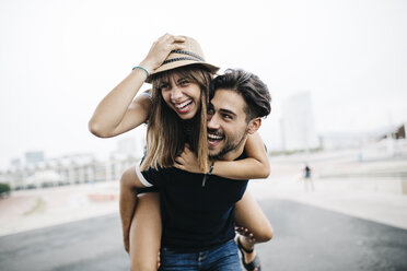 Spain, Barcelona, young man giving his girlfriend a piggyback ride - JRFF000141