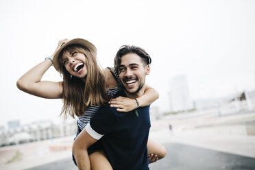 Spain, Barcelona, young man giving his girlfriend a piggyback ride - JRFF000142