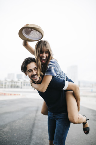 Spain, Barcelona, young man giving his girlfriend a piggyback ride stock photo