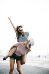 Spain, Barcelona, young woman giving her friend a piggyback ride - JRFF000144
