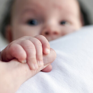 Die Hand eines kleinen Babys greift nach dem Daumen einer reifen Frau - HOHF001366