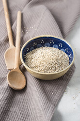 Bowl of quinoa with wooden spoons and kitchen towel - MYF001171