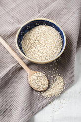 Bowl of quinoa with wooden spoons and kitchen towel - MYF001172