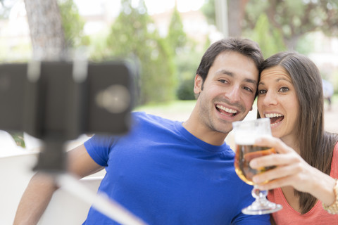 Happy couple using selfie stick for taking a selfie with smartphone stock photo