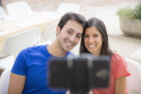 Happy couple using selfie stick for taking a selfie with smartphone - ERLF000064