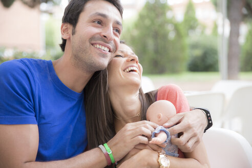 Laughing couple playing with a baby doll - ERLF000065