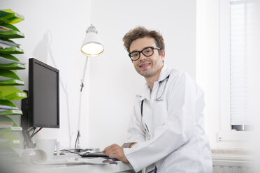 Porträt eines lächelnden Arztes, der am Schreibtisch sitzt - FKF001445