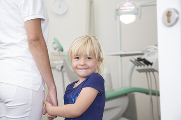 Dental assistant holding girl's hand before treatment - FKF001464