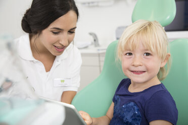 Zahnarzt und lächelndes Mädchen mit digitalem Tablet im Zahnarztstuhl - FKF001473