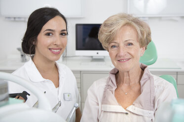 Dentist and smiling senior woman in dentist's chair - FKF001481