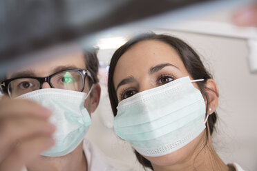 Two doctors with mouth masks looking at x-ray image - FKF001511