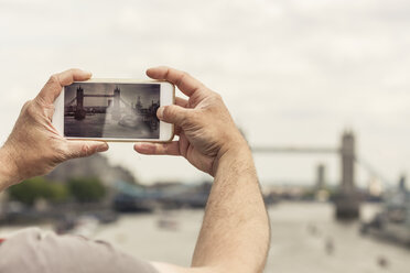 UK, London, man taking photo of Tower Bridge with his smartphone - ZMF000434