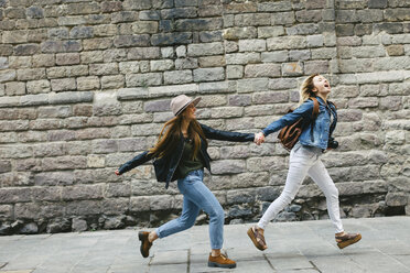Spanien, Barcelona, zwei junge Frauen laufen Hand in Hand durch die Stadt - EBSF000939