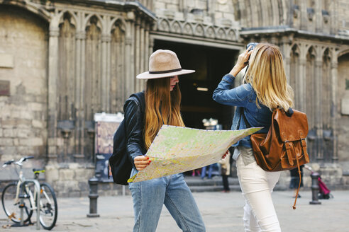Spanien, Barcelona, zwei junge Frauen auf einem Platz mit Kamera und Landkarte - EBS000943