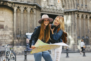 Spain, Barcelona, two happy young women with camera and map - EBS000944