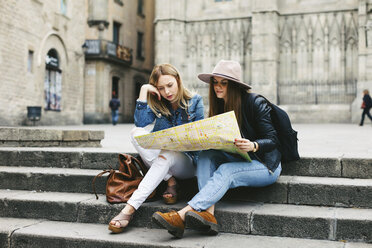 Spain, Barcelona, two young women reading map on stairs - EBS000958