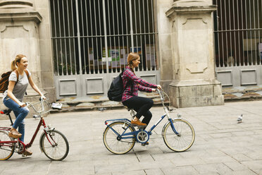 Spain, Barcelona, two young women riding bicycle in the city - EBSF000968