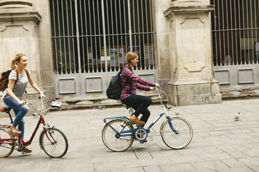 Spanien, Barcelona, zwei junge Frauen beim Fahrradfahren in der Stadt - EBSF000968