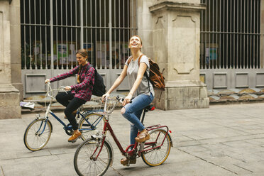 Spain, Barcelona, two young women riding bicycle in the city - EBSF000969