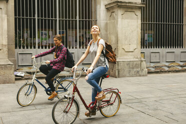 Spanien, Barcelona, zwei junge Frauen beim Fahrradfahren in der Stadt - EBSF000969
