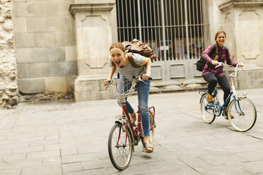 Spanien, Barcelona, zwei glückliche junge Frauen beim Fahrradfahren in der Stadt - EBSF000970