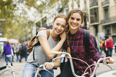 Spain, Barcelona, two young women on bicycles in the city - EBSF000971
