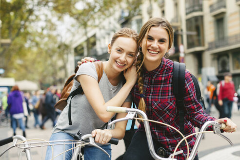 Spanien, Barcelona, zwei junge Frauen auf Fahrrädern in der Stadt - EBSF000971