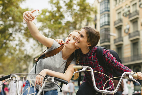 Spanien, Barcelona, zwei junge Frauen auf Fahrrädern machen ein Selfie - EBSF000973