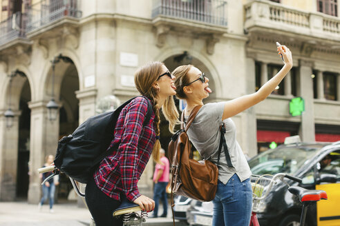 Spanien, Barcelona, zwei verspielte junge Frauen machen ein Selfie - EBSF000978