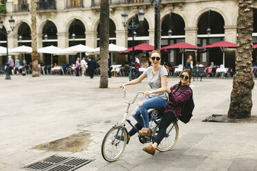 Spain, Barcelona, two happy young women sharing bicycle in the city - EBSF000980