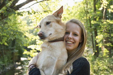 Portrait of smiling young woman holding her dog - CRF002722