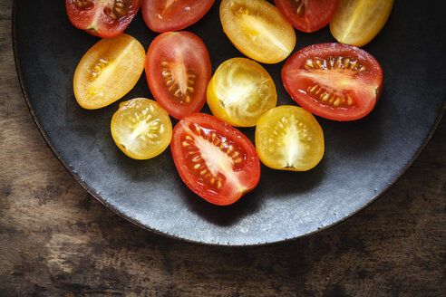 Halbierte gelbe und rote Kirschtomaten auf dem Teller - EVGF002472