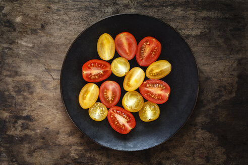 Halbierte gelbe und rote Kirschtomaten auf dem Teller - EVGF002475