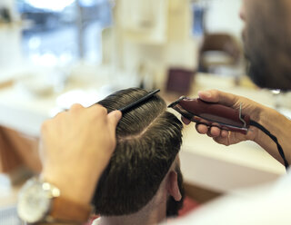 Friseur schneidet einem Kunden die Haare - MGOF000890