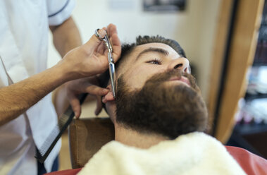 Barbier schneidet Bart eines Kunden - MGOF000911