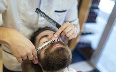 Barbier schneidet Bart eines Kunden - MGOF000913