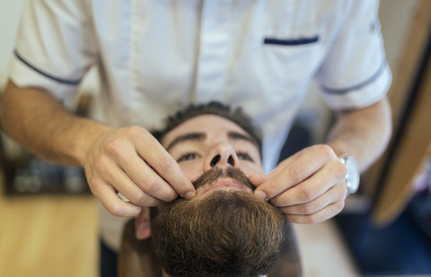 Friseur, der den Bart eines Kunden zurechtrückt, lizenzfreies Stockfoto