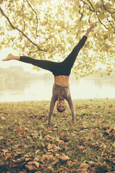 Woman doing a cartwheel in autmny park - MFF002445