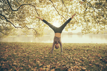 Woman doing a cartwheel in autmny park - MFF002446