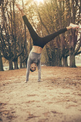 Woman doing a cartwheel in autmny park - MFF002448