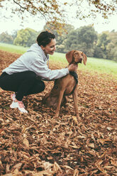 Woman talking to her Vizsla dog in park during autumn - MFF002455