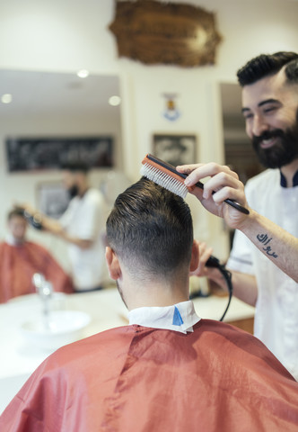 Friseur bürstet das Haar eines Kunden, lizenzfreies Stockfoto