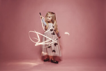 Little girl lightpainting with a torch in front of a pink background - IPF000255
