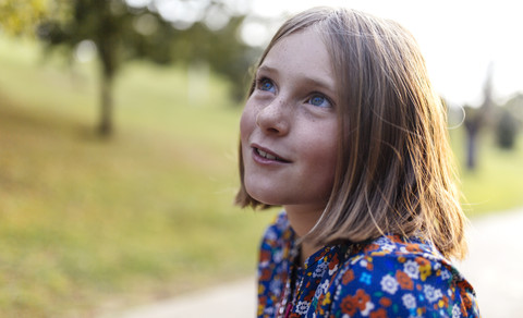 Portrait of smiling blond girl with freckles looking up stock photo