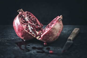 Sliced pomegranate and a kitchen knife on slate - IPF000260