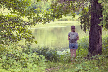 Russland, Sankt Petersburg, Rückenansicht einer Frau, die im Shuvalovsky Park auf das Wasser schaut - KNTF000144