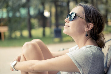 Frau mit Sonnenbrille entspannt in einem Park - KNTF000147