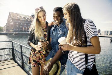 Germany, Duisburg, three young people looking at smartphone at Media Harbour - GDF000883