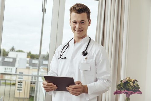 Junger Arzt im Krankenzimmer mit digitalem Tablet - MFF002485